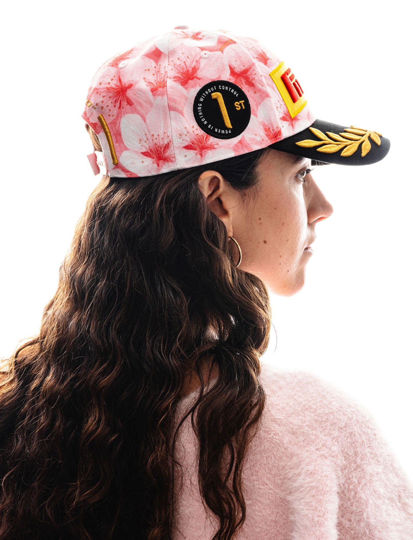 Person wearing a floral-patterned cap with Pirelli logo on a white background
