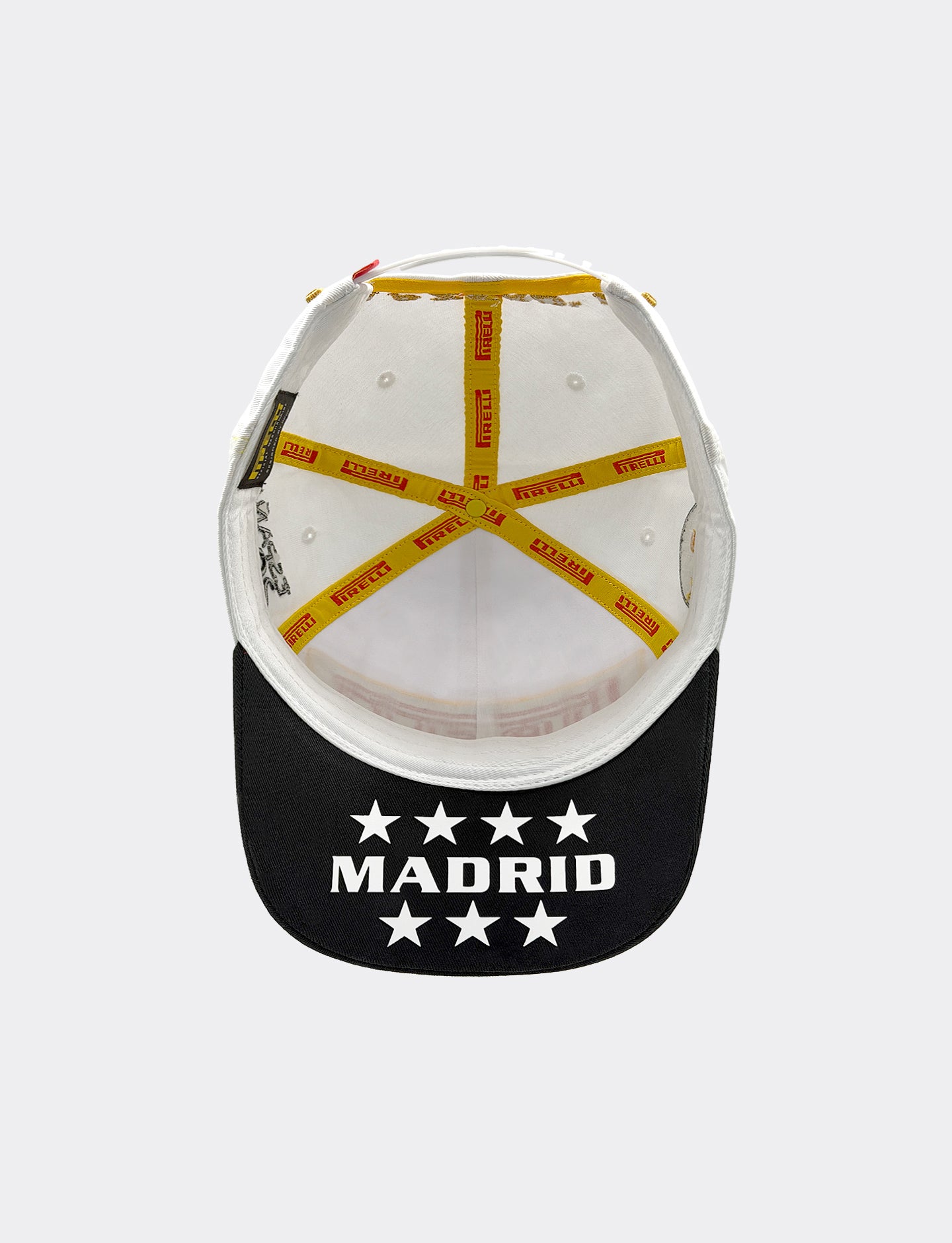 Pirelli Podium Cap 2026 Madrid - bottom view showing inside of white crown with yellow and red Pirelli taping, black visor with 'MADRID' and 7 white stars printed on visor