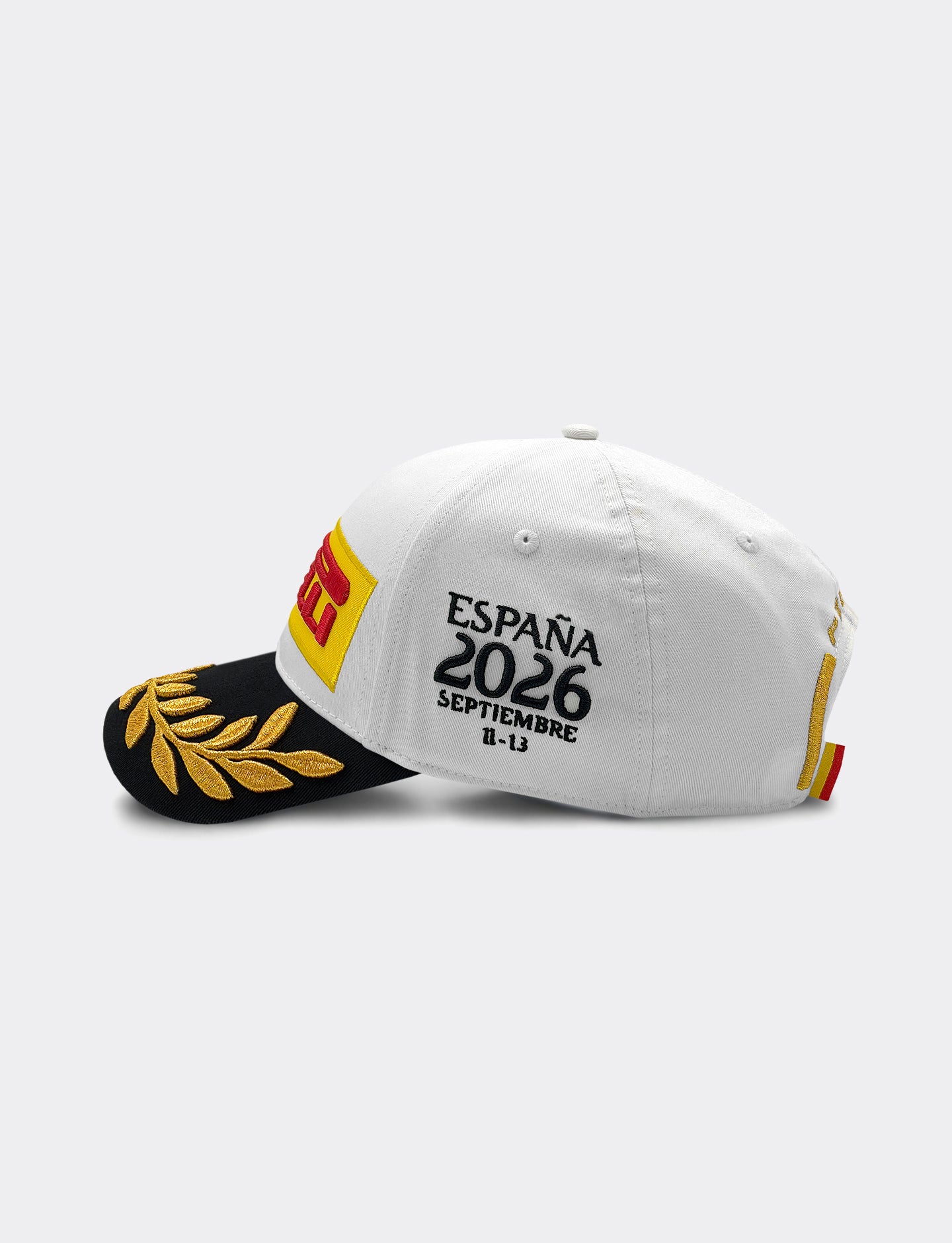 Pirelli Podium Cap 2026 Madrid - left view, white cap with black visor with gold laurel embroidery. 'ESPAÑA 2026 SEPTIEMBRE 11-13" embroidered in black on left panel