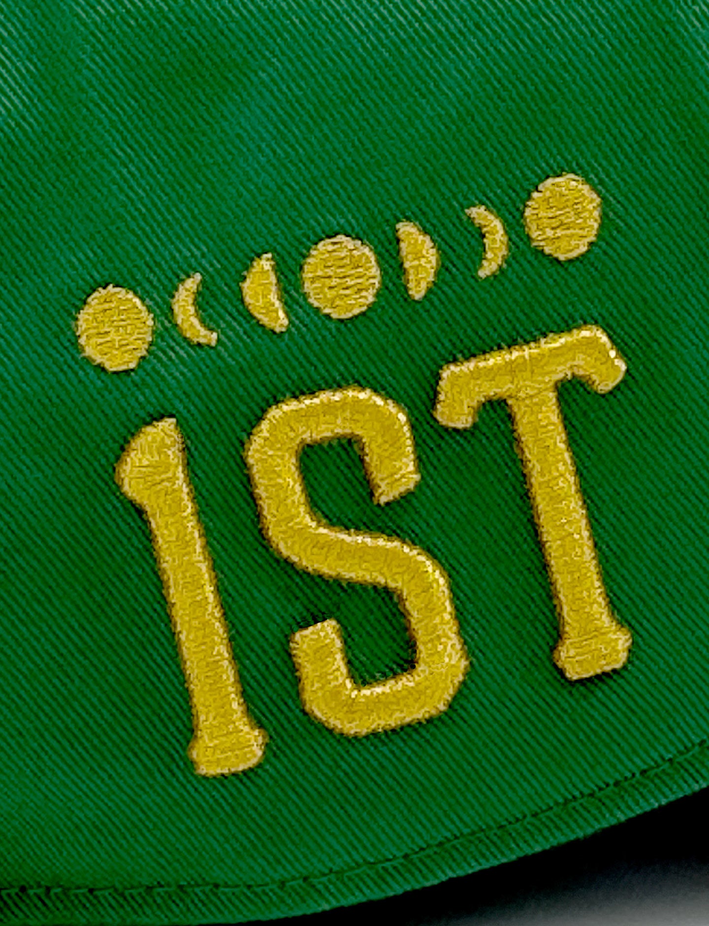 closeup of '1st' embroidery on green Pirelli cap