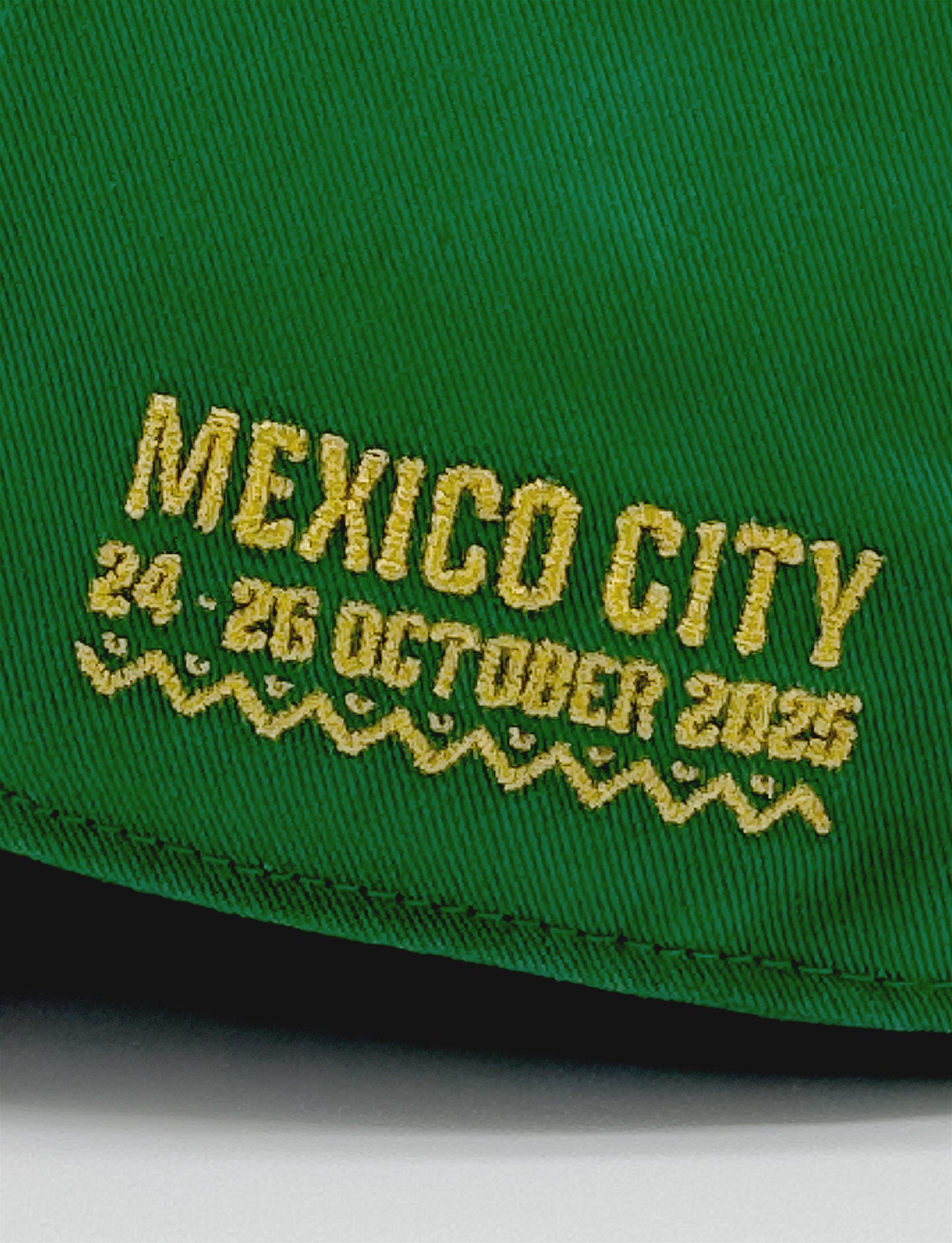 Green cap with yellow embroidered text 'Mexico City 24-26 October 2025' on a white background