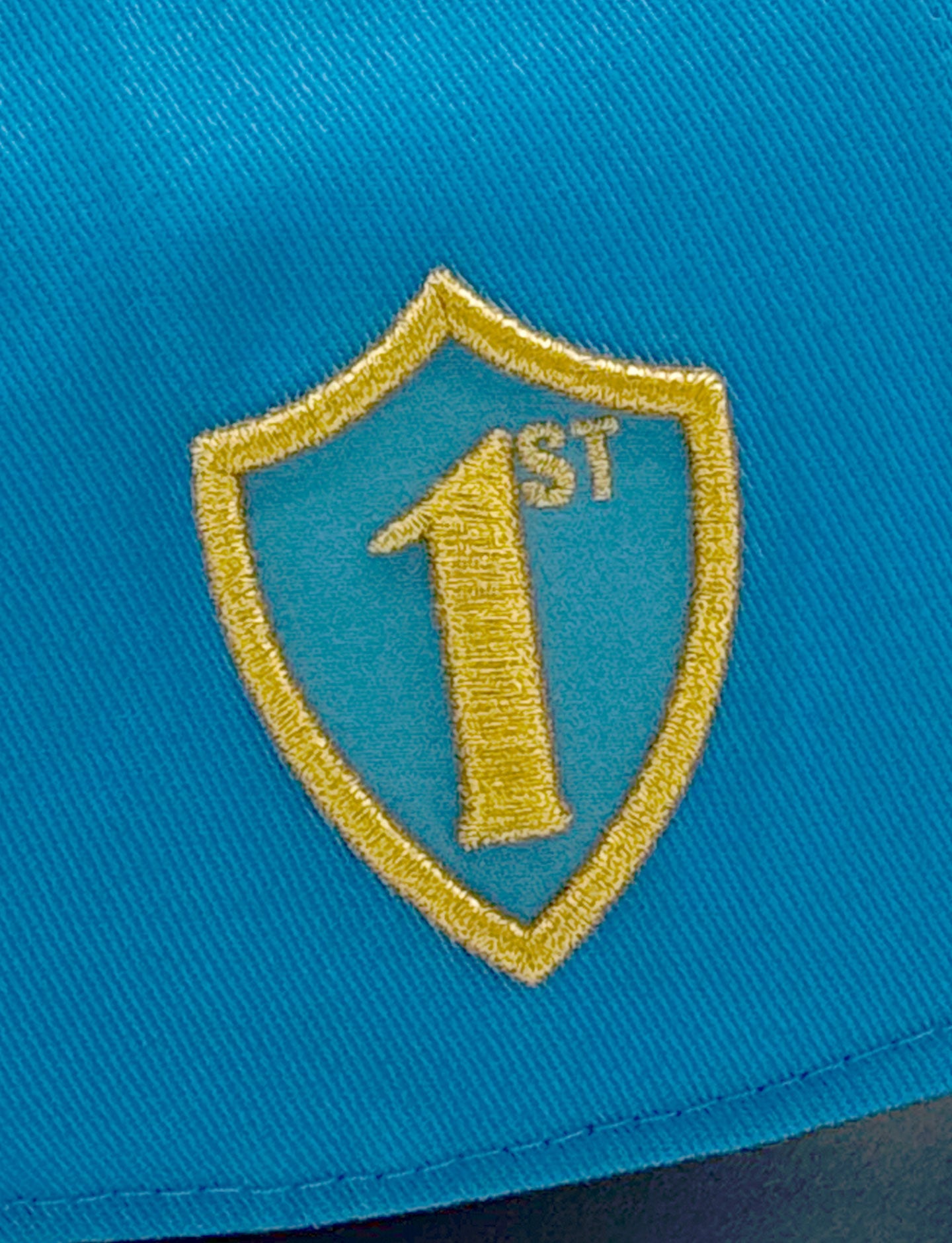 Gold shield emblem with '1st' on a blue Pirelli cap