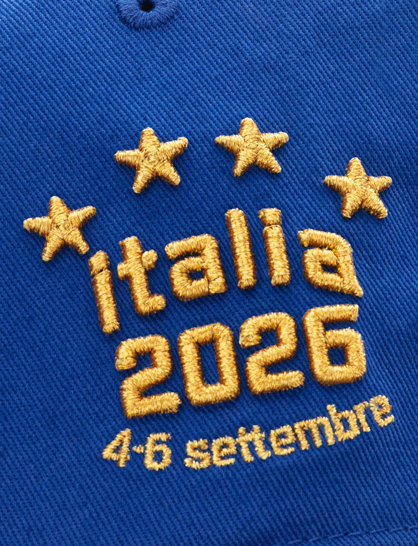 Close-up of a royal blue Pirelli Podium cap with gold embroidered text reading 'italia 2026' and '4-6 settembre' beneath it, plus four gold stars above.