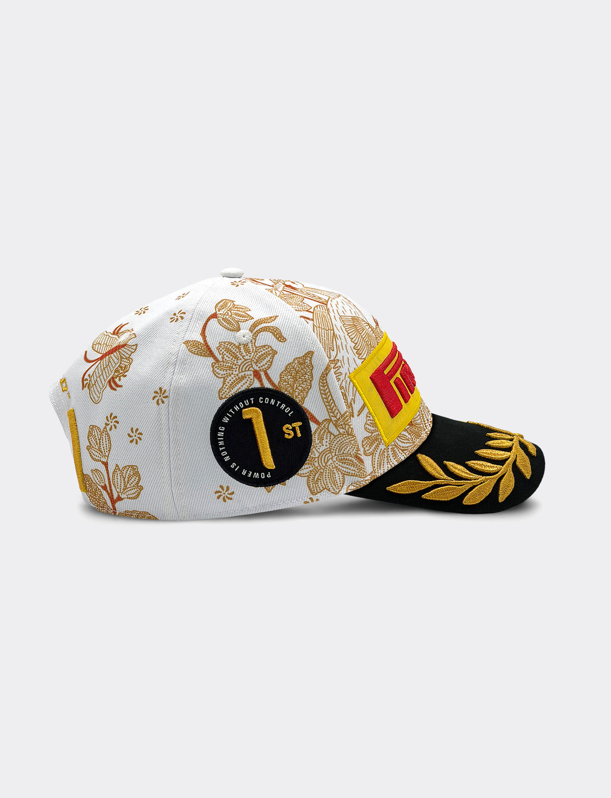 Ride side view of Pirelli Podium Cap 2026 Singapore featuring a white crown with orange/brown floral patterns, a black brim with gold leaf embroidery, and yellow and red graphic Pirelli logo on the front.