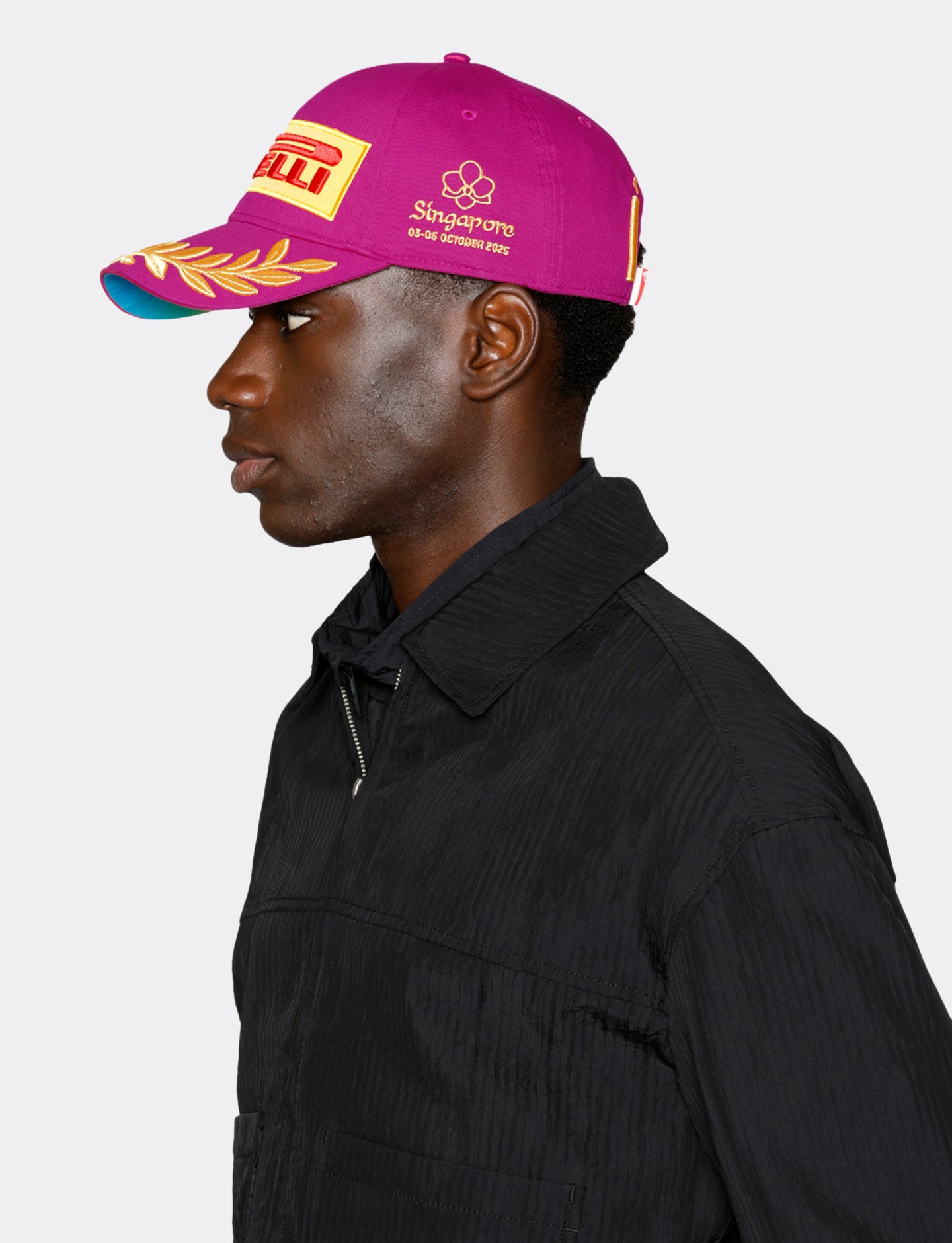 Person wearing a magenta Pirelli cap with branding on a white background