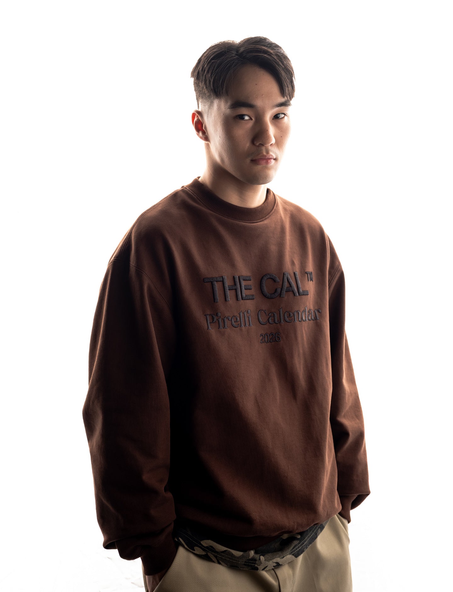 Person wearing a brown Pirelli sweatshirt with text on a white background