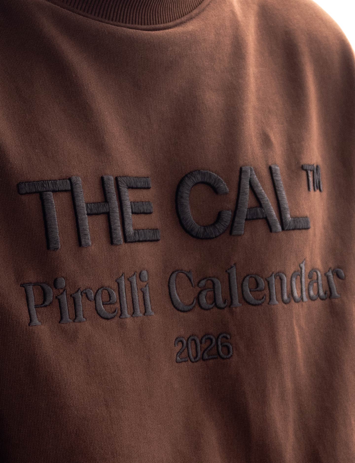 Brown sweatshirt with 'THE CAL Pirelli Calendar 2026' text