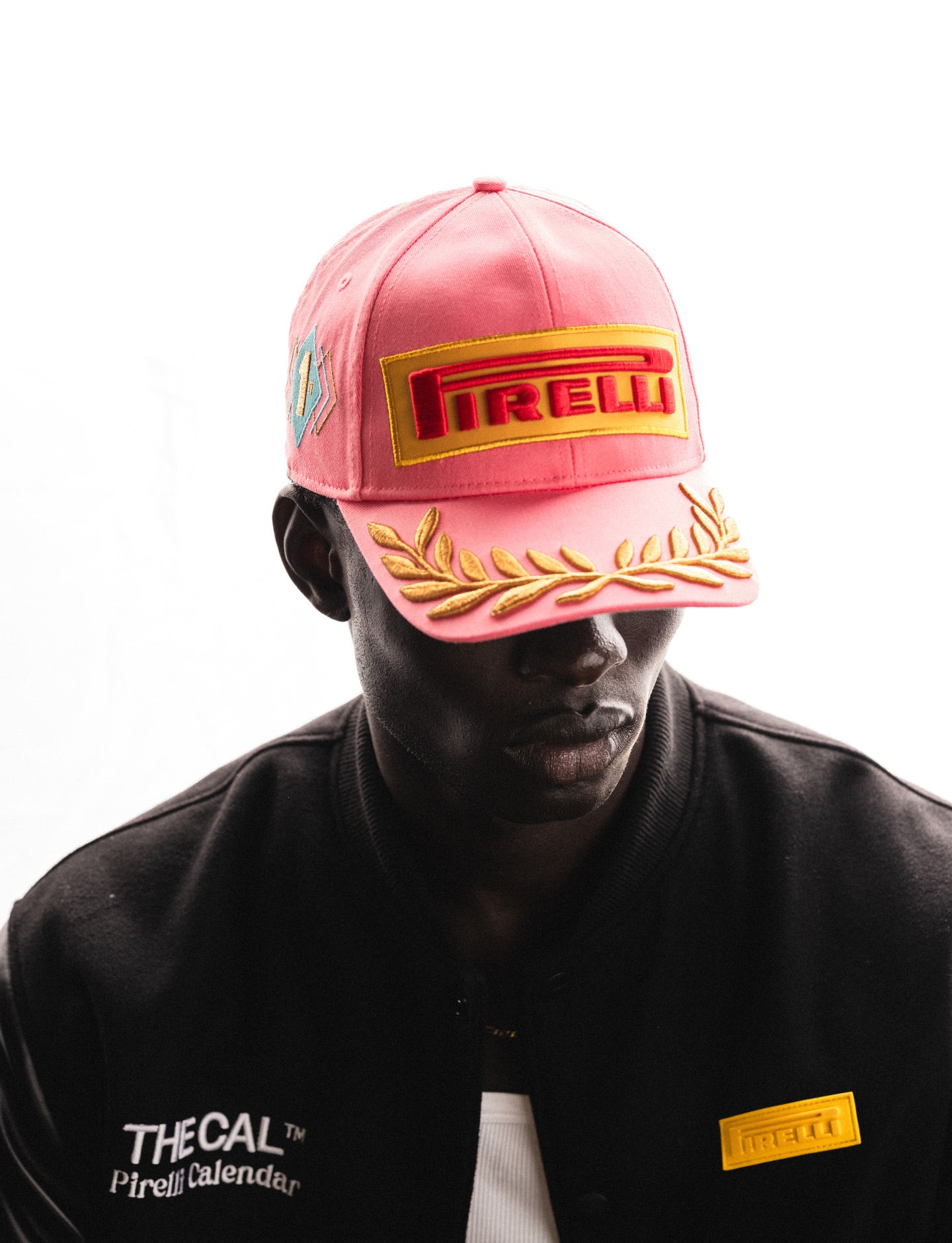 Person wearing a pink cap and black jacket with Pirelli logo on a white background