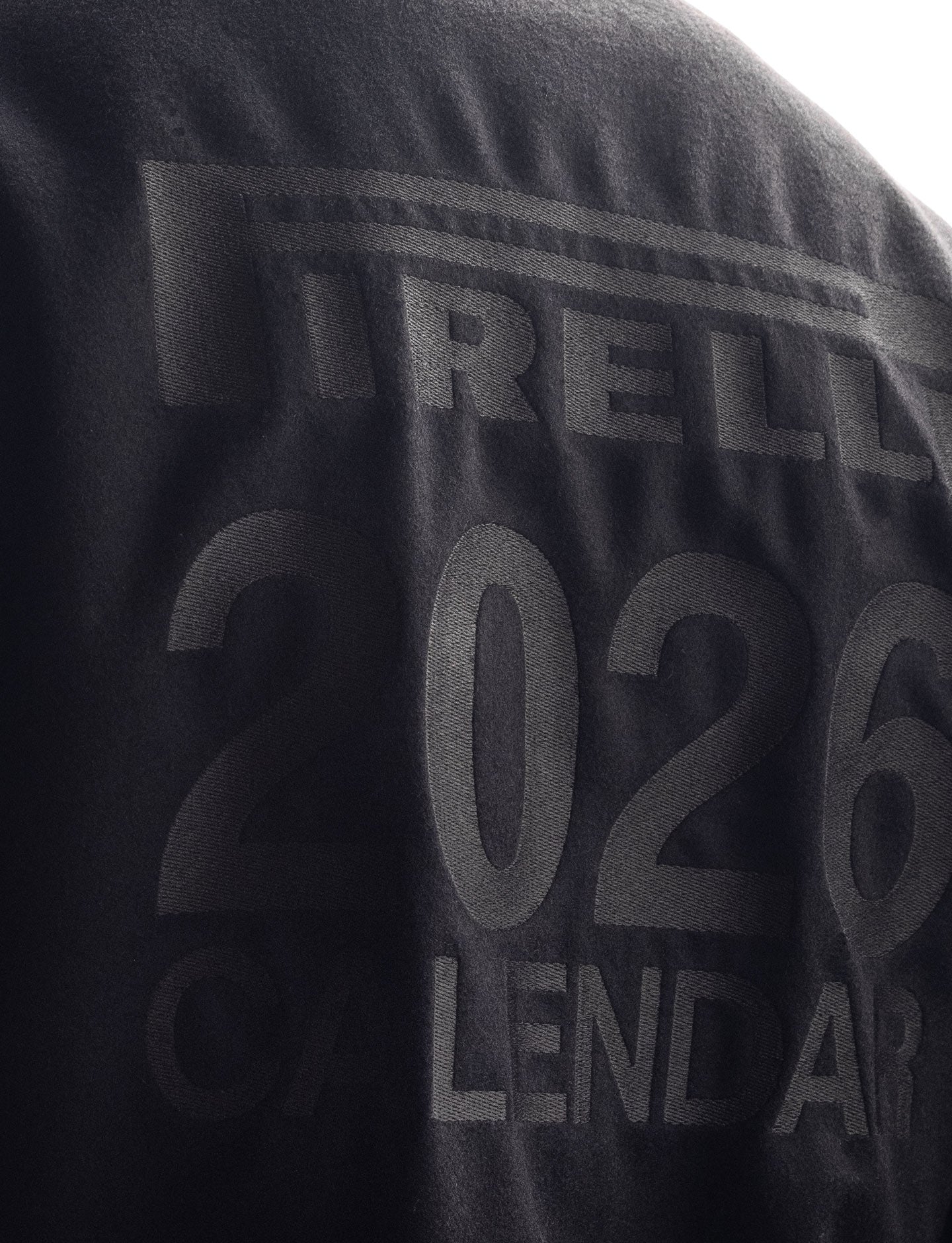 Black jacket with 'Pirelli' and '2026' branding on a dark background