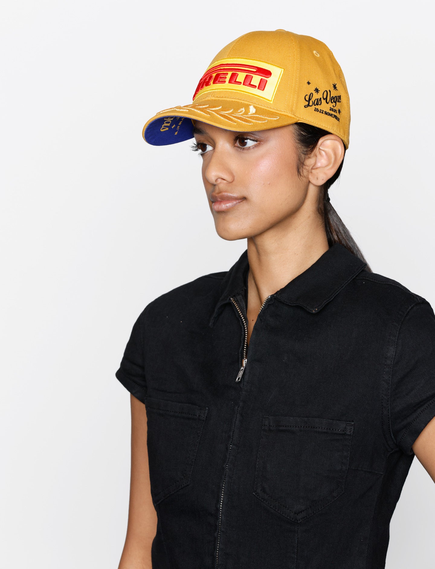 Person wearing a gold cap with Pirelli logo on a white background