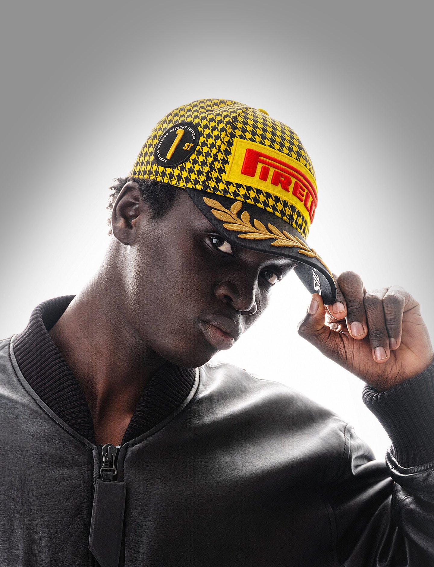 Person wearing a yellow and black checkered Pirelli Podium Cap 2026 Silverstone F1®